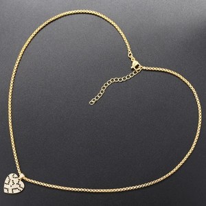 Macro shot of gold heart pendant with black and clear pavé crystals on a cable chain