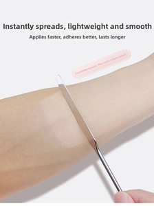 Close-up of stainless steel makeup spatula spreading liquid foundation evenly on arm