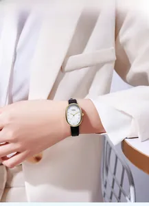 Elegant gold oval watch with white textured dial and black leather strap worn on wrist