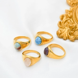 Flat lay of four vintage gold rings with colorful agate and stones on white silk