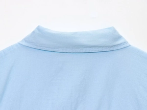 Close-up of light blue cotton linen shirt collar with neat stitching and fabric texture