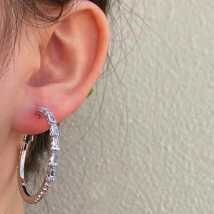 Close-up detail of silver hoop earrings with shimmering pave-set zircon stones on model