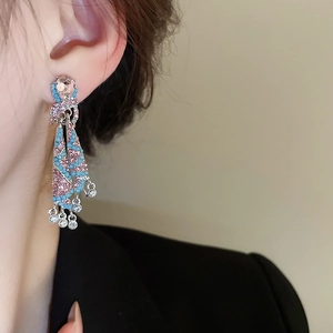 Detailed view of colorful tassel earrings with pink and turquoise rhinestones on model