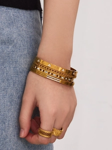 Détail de bracelets dorés empilés avec motifs de cœur et pavé de zircons étincelants