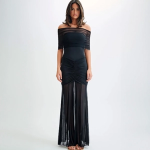 Detail of elegant black off-shoulder dress with ruching and sheer mesh patchwork hem