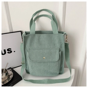 Detailed view of the green corduroy tote bag featuring front pocket and shoulder strap