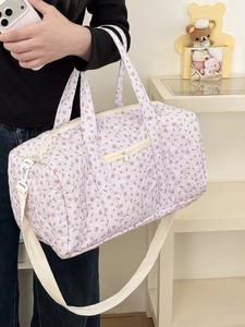 Dettaglio borsa da viaggio trapuntata a fiori con manici bianchi e tracolla regolabile