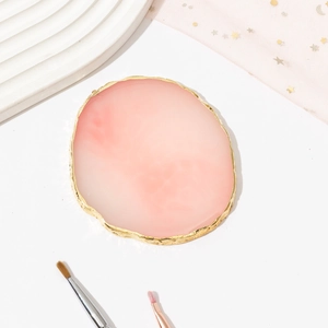 Detailed top view of pink resin agate nail palette with gold rim on white background
