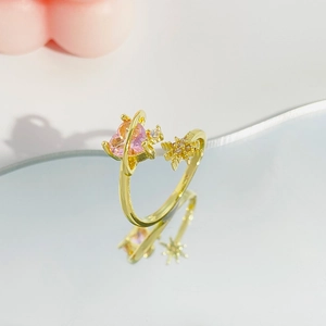 Golden open ring with pink heart stone and star detail on mirror background