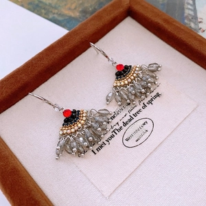 Macro view of vintage fan-shaped earrings with red gemstone and grey droplet tassels