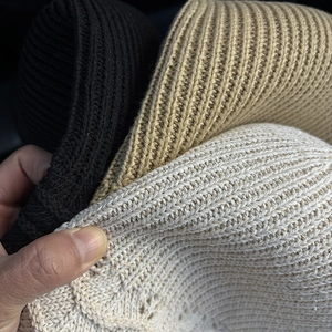 Detailed macro view of thick ribbed knit fabric in black, khaki, and beige colors