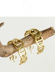 Detailed view of 18K gold plated titanium steel chain earrings on a rustic wood branch