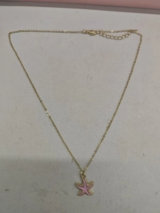 Detail of gold chain necklace featuring a pink starfish pendant and lobster clasp closure