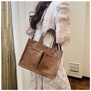Detailed view of a vintage brown PU leather tote bag with two front pockets on a model