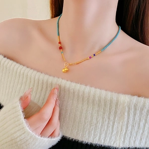 Detail of colorful beads and gold gourd pendant necklace worn on woman neck