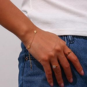 Detail of 18K gold plated clover charm bracelet and sparkling rings on a person