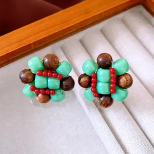 Ethnic style flower cluster earrings with green resin and brown wood beads on a tray