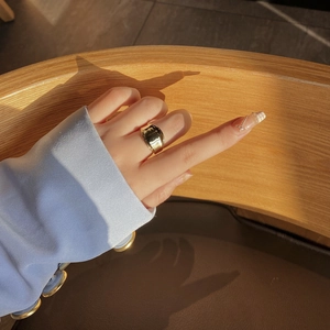 Artistic lighting on wide gold minimalist ring worn on model finger in natural setting
