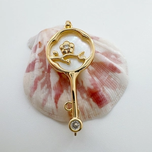Detailed view of 18K gold-plated plum blossom fan pendant on a shell for jewelry making