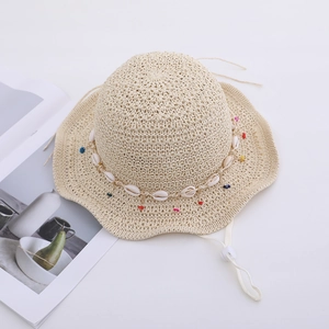 Close-up of summer straw sun hat featuring seashell beads and a wavy brim edge