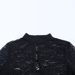 Dettaglio top in pizzo nero con collo alto e chiusura con bottoni raffinati