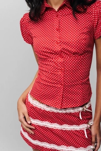 Detailed view of red polka dot blouse with white lace trim and pink floral embroidery