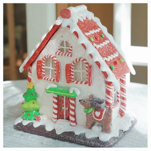 Detail of a lighted clay candy house with red roof, Christmas tree, and reindeer figure