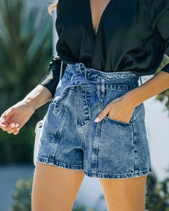 Dettaglio degli shorts in denim a vita alta con cintura a fiocco e grandi tasche laterali