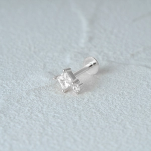 Macro shot of silver S925 star stud earring with square zircon on textured surface