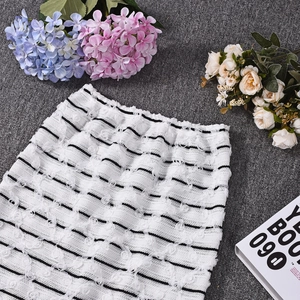 Detail of white pencil skirt with 3D floral texture and classic black stripes pattern