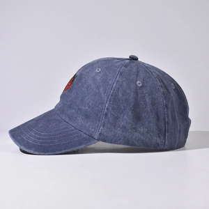 Dettaglio del ricamo a fragola e della trama in denim blu lavato del cappellino