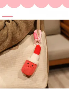 Cute plush lipstick keychain with smile embroidery hanging on a beige handbag