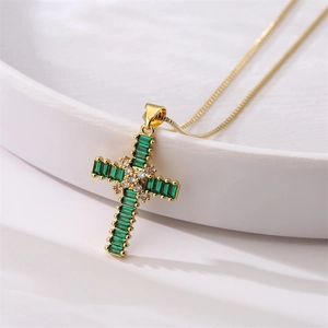 Detailed macro view of a gold cross pendant set with green and white gemstones