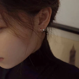 Elegant double-layered pearl earrings in silver finish worn by a model in a close-up view