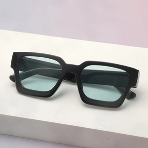 Close-up of thick square black frame sunglasses with light blue lenses on white stand