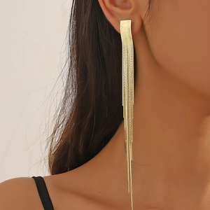 Close-up of elegant gold tassel earrings with long metallic chains on a model