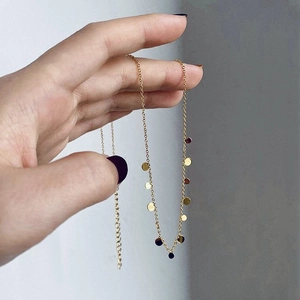 Close-up of a gold titanium steel necklace featuring small flat disc charms and extension chain