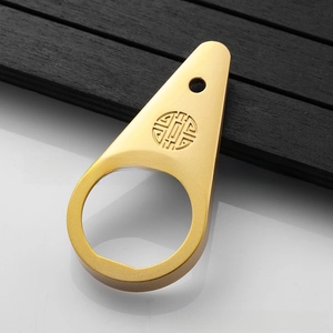 Macro detail of teardrop metal bottle opener with traditional Chinese fret pattern