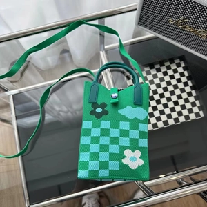 Détail du mini sac tricoté vert à damier avec boucle en métal et perle bleue sur verre