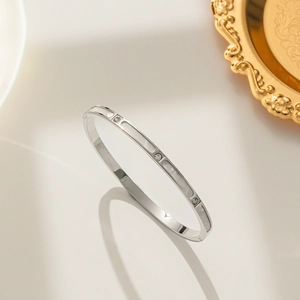 Minimalist silver steel bangle with white shell inlay and zircon accents on a gold tray