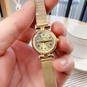 Vintage gold women's watch with mesh strap and Roman numerals in a lifestyle setting
