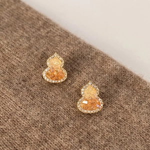 Elegant gold-plated gourd earrings with crystals and amber stones on textured fabric