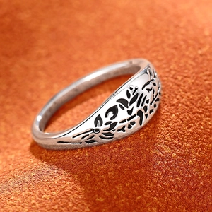 Macro view of vintage silver floral ring with black engraved textures on orange background