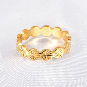 Close-up of gold-plated flower ring with starburst engraving on white silk fabric