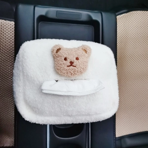 Close-up of white plush tissue box cover with cute brown teddy bear embroidery on car console
