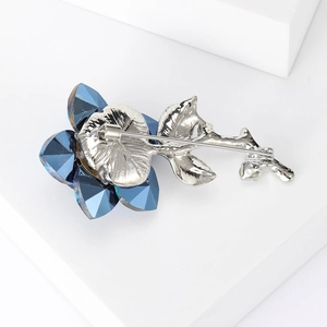 Elegant blue crystal floral brooch with silver finish on a white geometric display