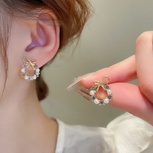 Elegant gold bow wreath earrings with white pearls and light blue gemstones on model