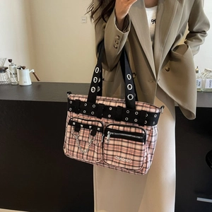 Pink plaid punk tote bag with metal eyelets and chain straps shown on a model