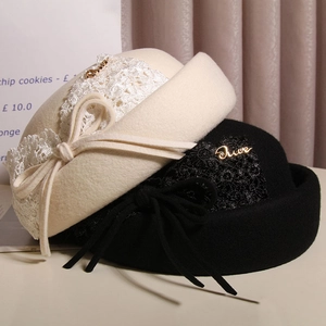 Detail of wool felt berets with elegant lace trim and chic bow accents on a white surface