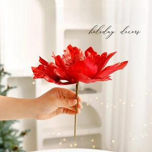 Sparkling red Christmas flower ornament held by hand for festive tree and wreath decoration